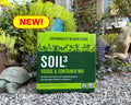 A green bag of Soil3 Veggie & Container Mix placed on a gravel surface with a garden and a stone sculpture of a turtle in the background. A 'NEW!' sticker is also visible on the top left corner of the image.
