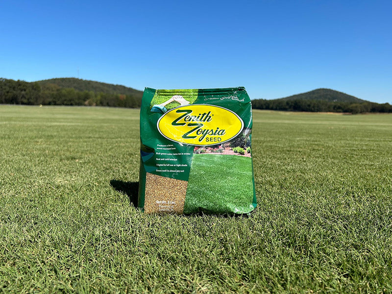 Bag of Zerith Zoysia seed on a grassy field with a clear blue sky
