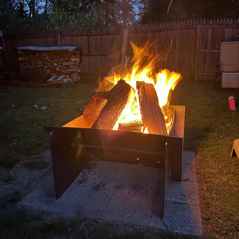 Customer fire pit lit at night by a fence